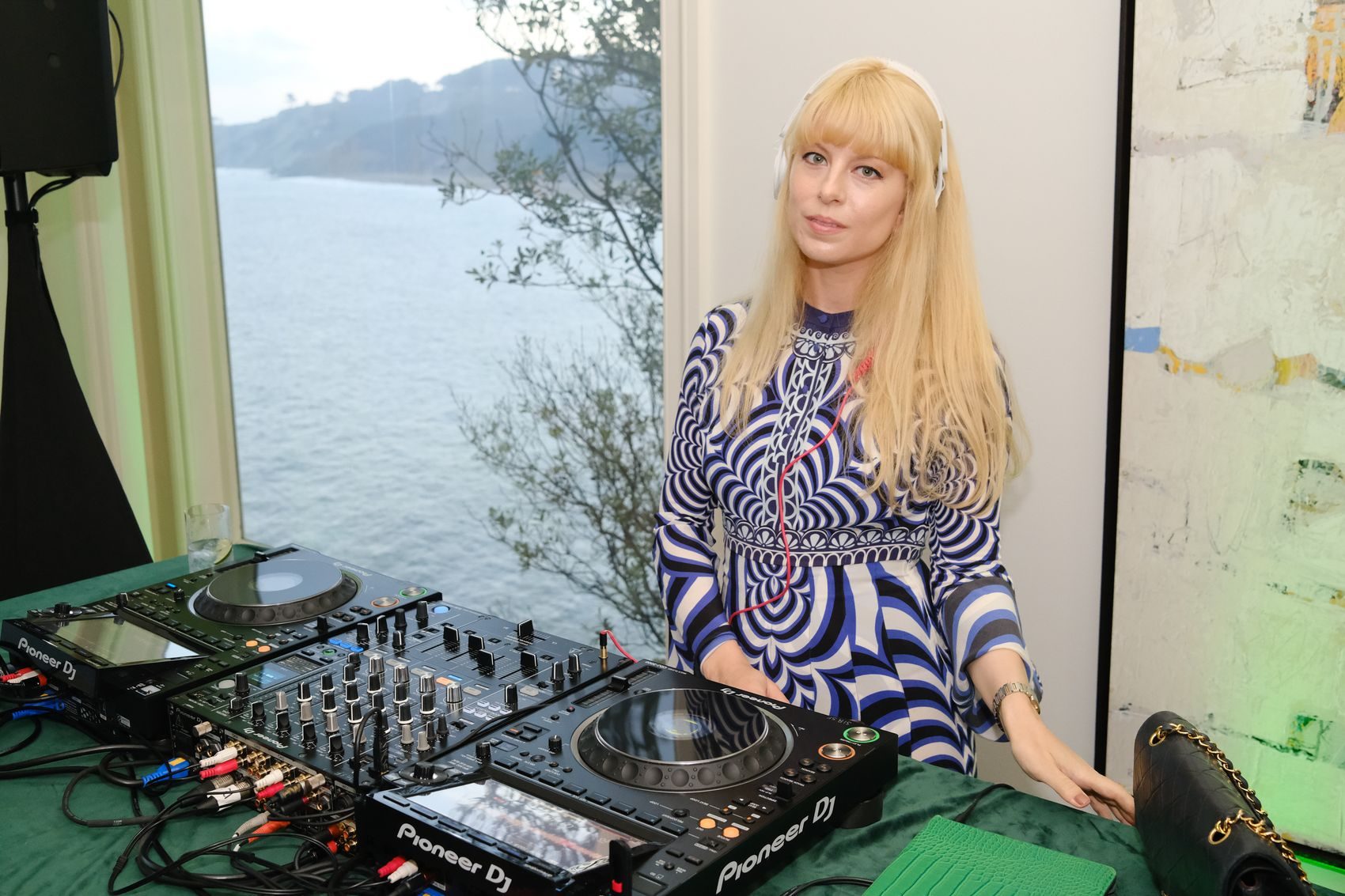 A DJ plays beside a window overlooking the bay