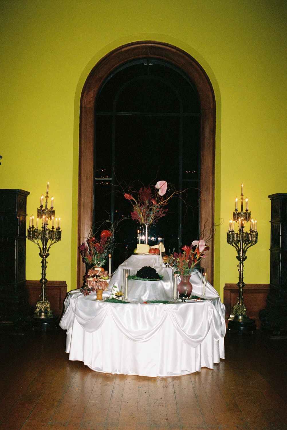A draped food table against a chartreuse wall and arched window