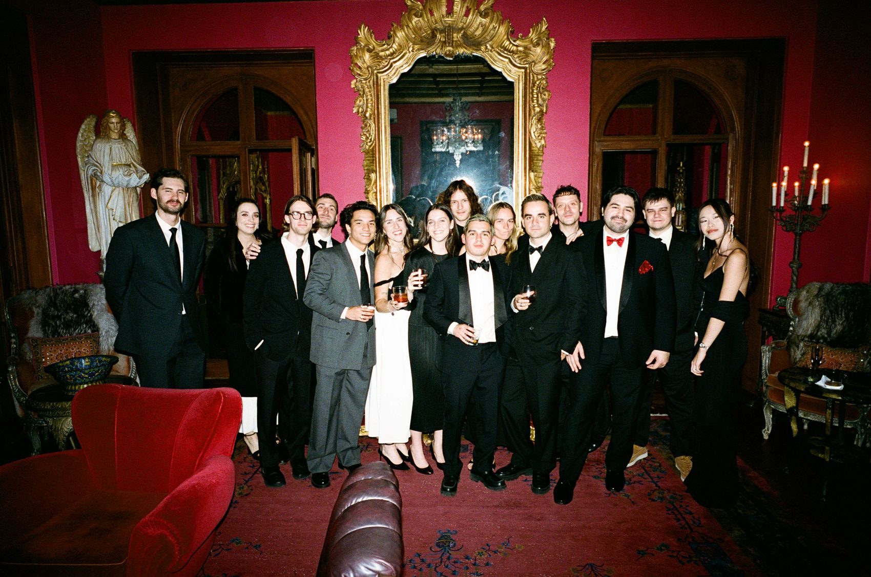 A full group portrait in a crimson drawing room