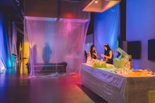 An immersive installation lit in blue and pink with draped sheeting