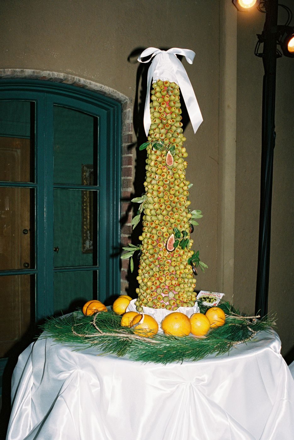 A tall tower built of green olives dressed with a ribbon