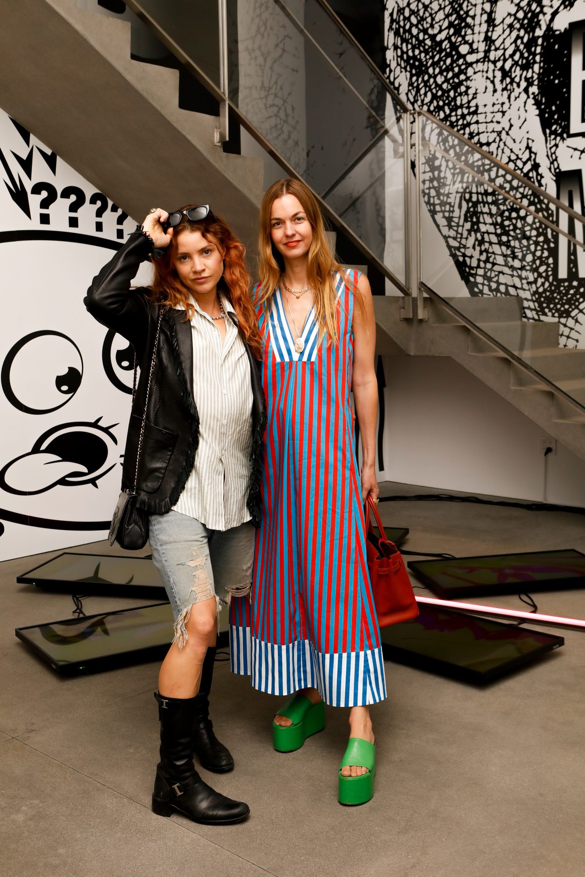 Two guests before a black-and-white cartoon mural and floor-set screens