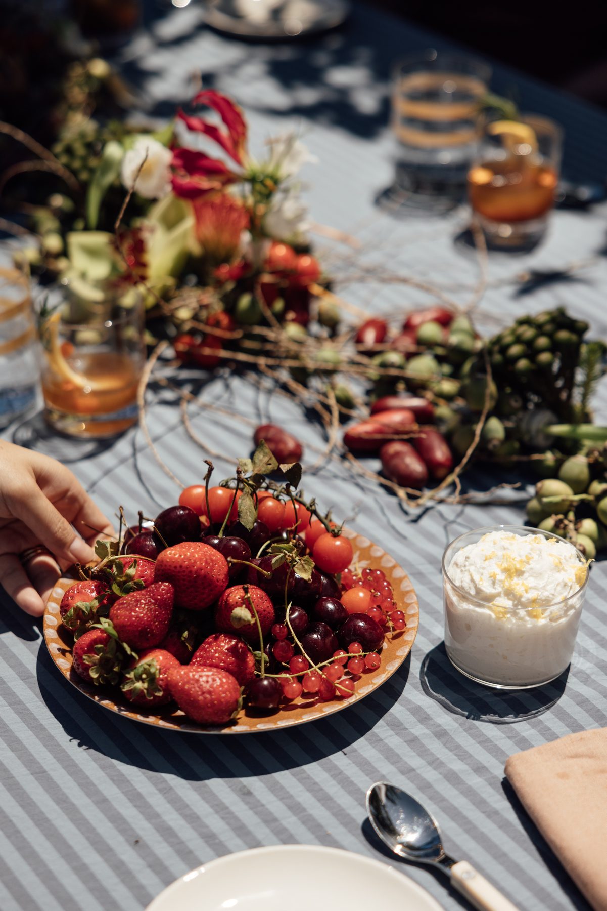 A plate of summer berries and cherries on a striped cloth