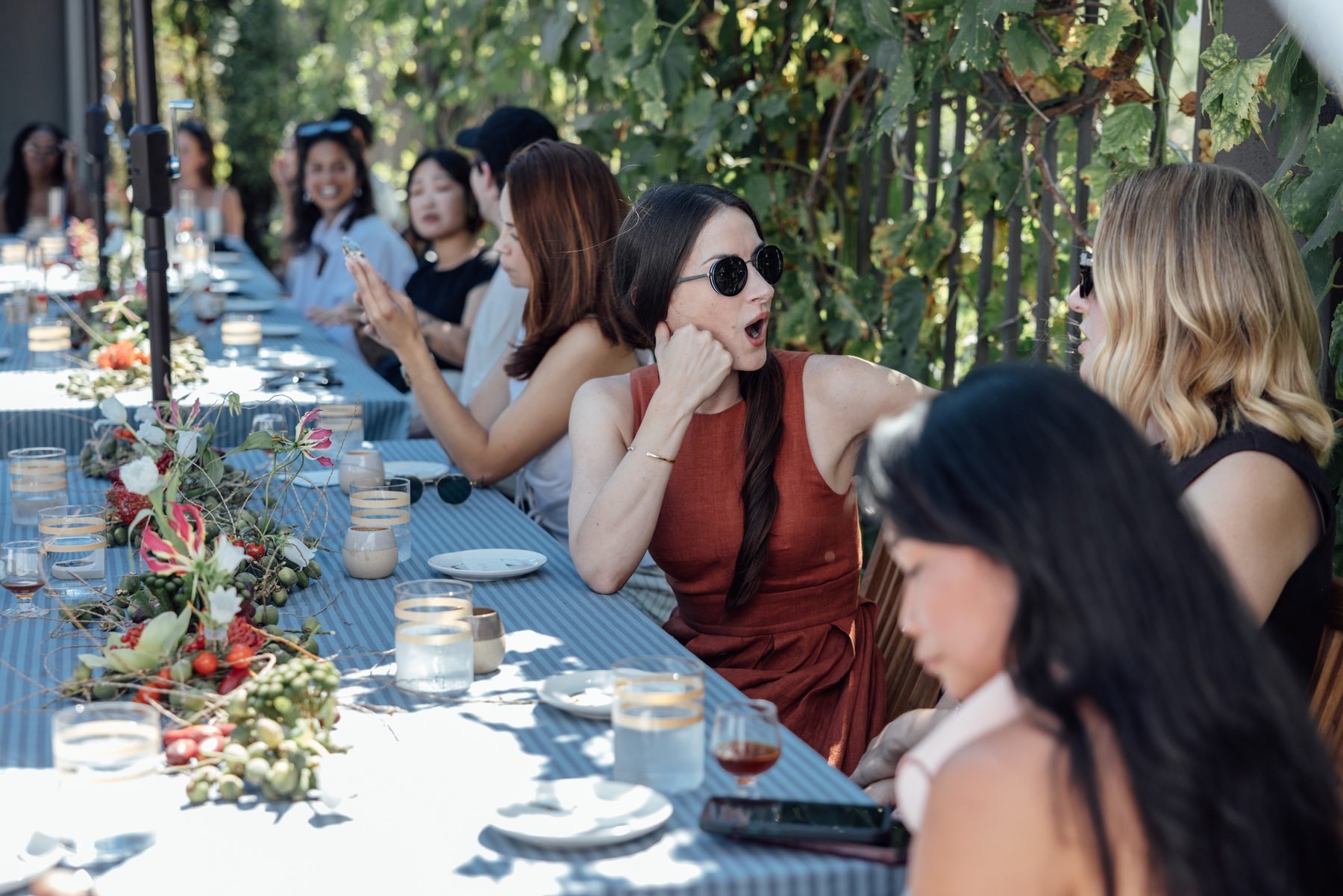 Guests in conversation at the sunlit poolside table