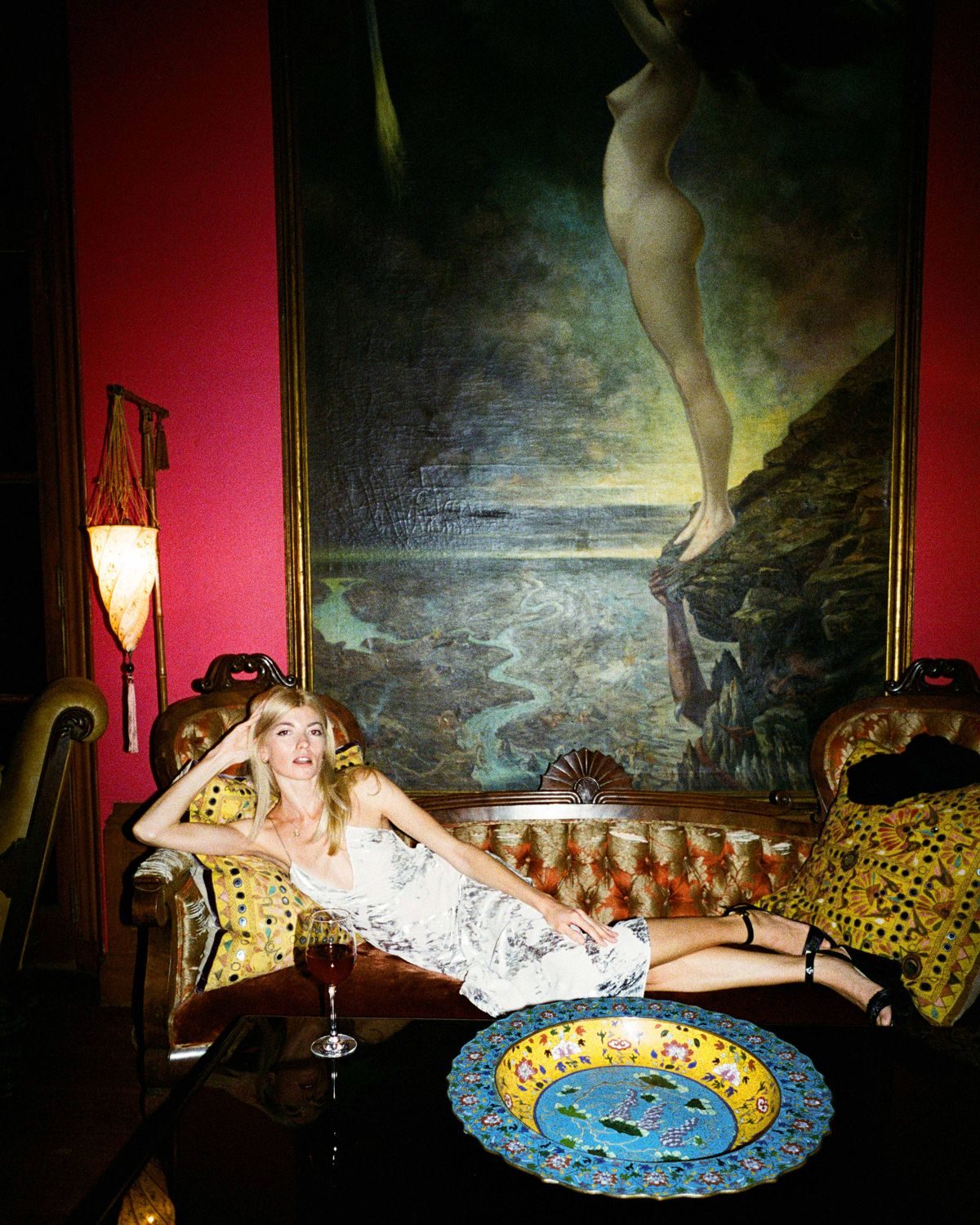 A guest reclines on an antique settee in a candlelit salon