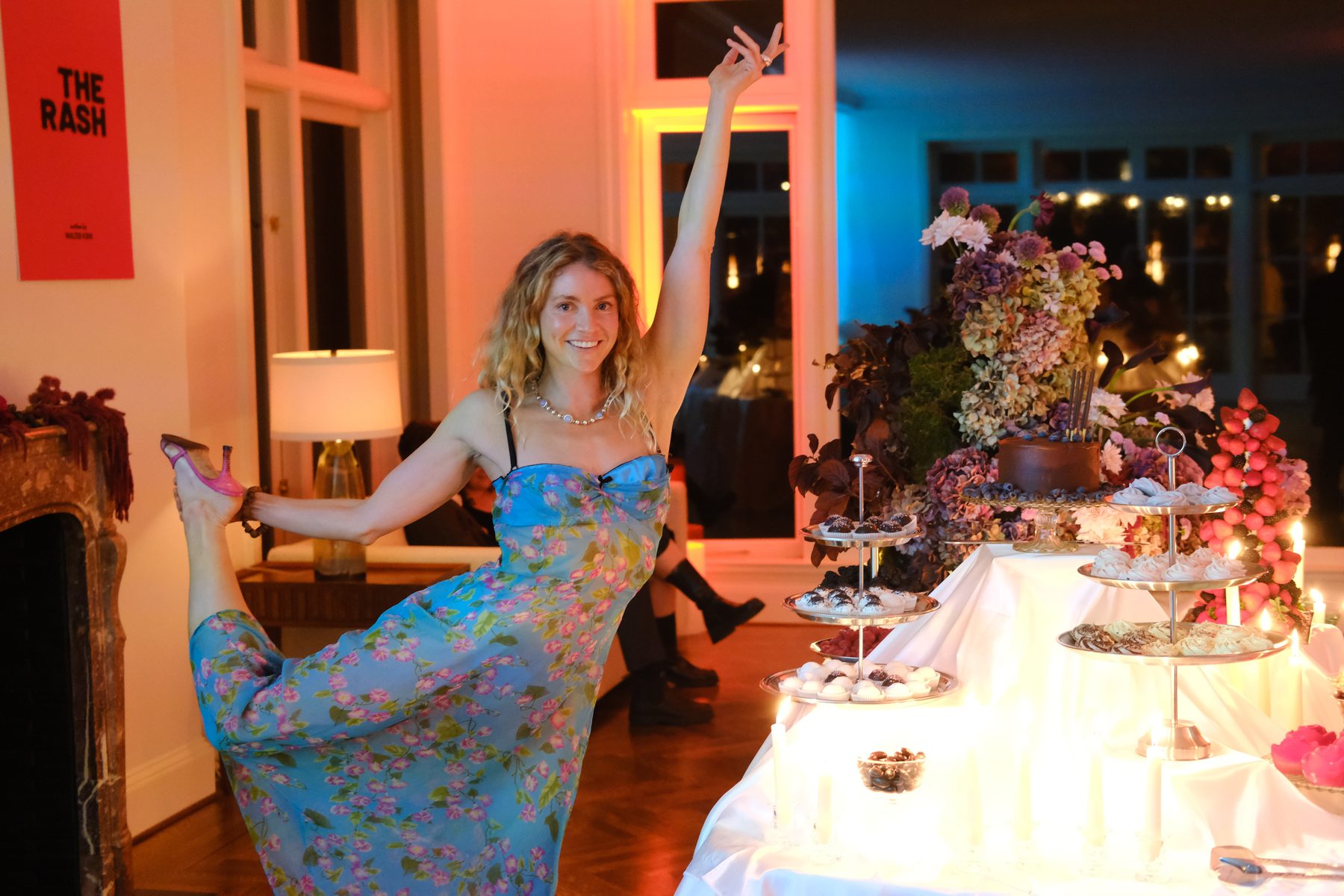A host poses beside a layered dessert and floral table